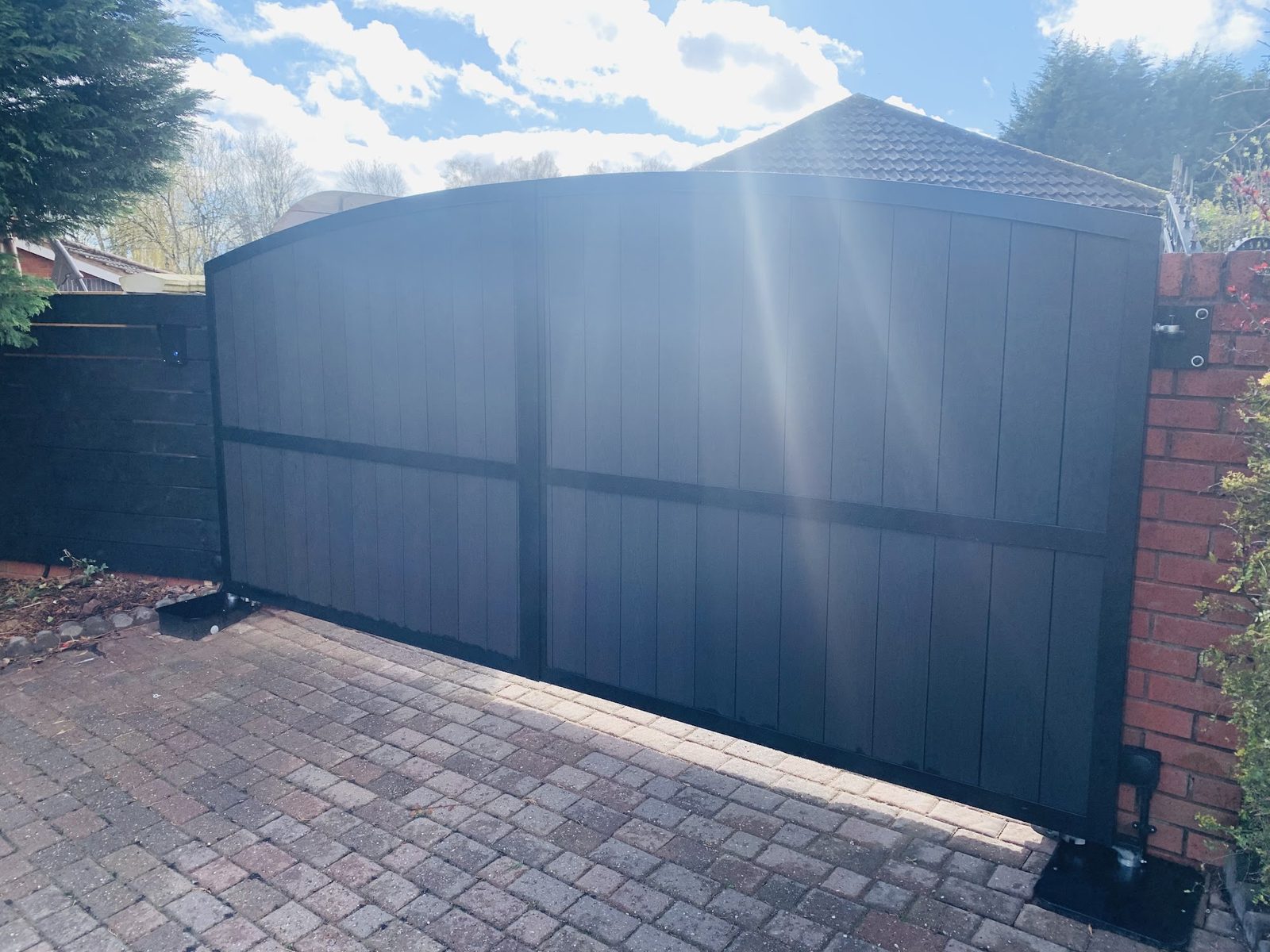 Wide sliding gate across a block paved commercial entrance